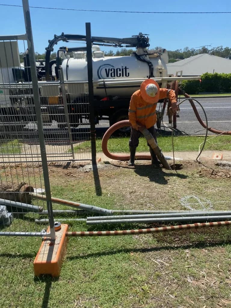 VACIT operator using a vacuum hose beside a branded truck